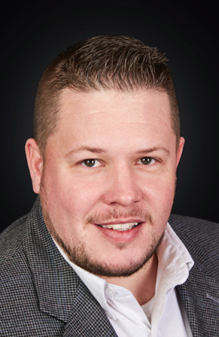 a man wearing a suit and tie smiling and looking at the camera