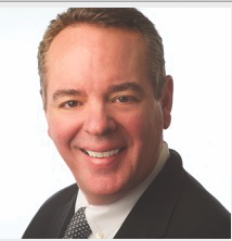 a man wearing a suit and tie smiling at the camera