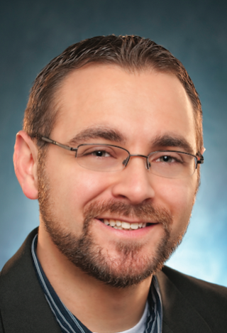 a man wearing glasses and smiling at the camera