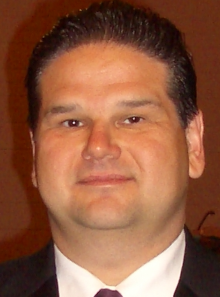 a man wearing a suit and tie smiling at the camera