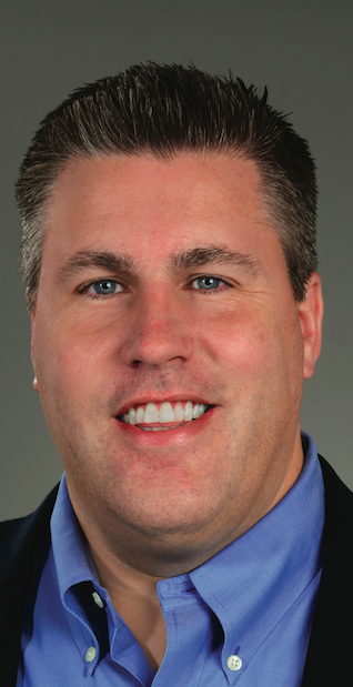 a man wearing a suit and tie smiling and looking at the camera