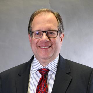 a man wearing a suit and tie smiling at the camera