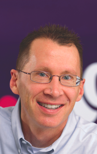 a man wearing glasses and smiling at the camera