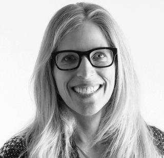 a close up of a person wearing glasses and smiling at the camera