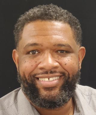 a man wearing a suit and tie smiling at the camera