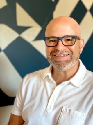 a man wearing glasses and smiling at the camera