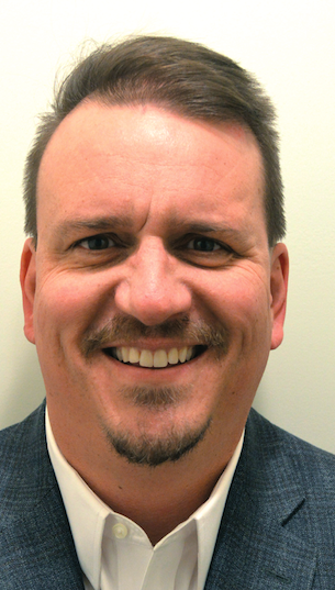 a man wearing a suit and tie smiling and looking at the camera