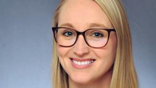 a woman wearing glasses and smiling at the camera