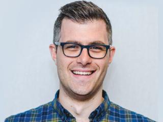 Daniel Ingram wearing glasses and smiling at the camera
