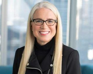 a woman wearing glasses and smiling at the camera