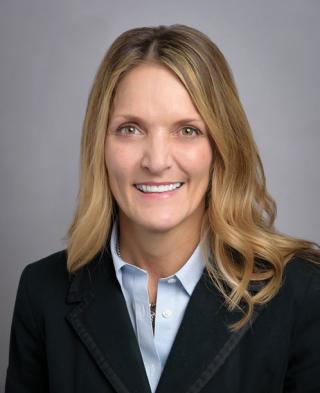 a woman wearing a suit and tie smiling at the camera