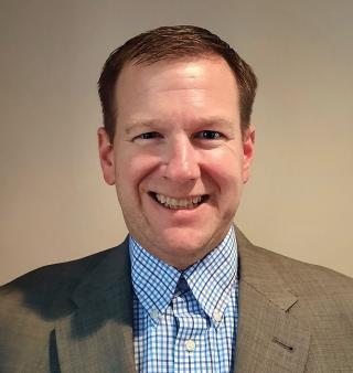 a man wearing a suit and tie smiling and looking at the camera